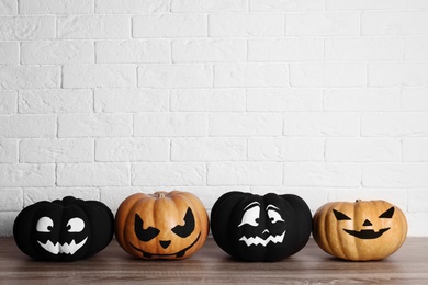 Pumpkins with scary faces near brick wall, space for text. Halloween decor