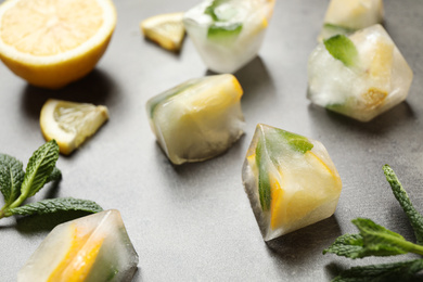 Photo of Ice cubes with lemon and mint on grey table, closeup