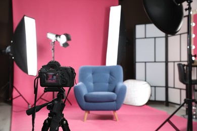 Photo of Stylish blue armchair in photo studio with professional equipment, focus on camera