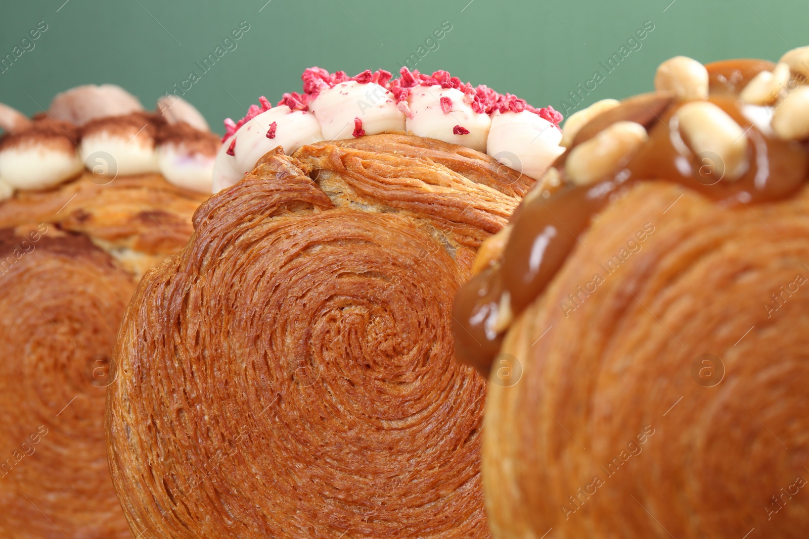 Photo of Crunchy round croissants on pale green background, closeup. Tasty puff pastry
