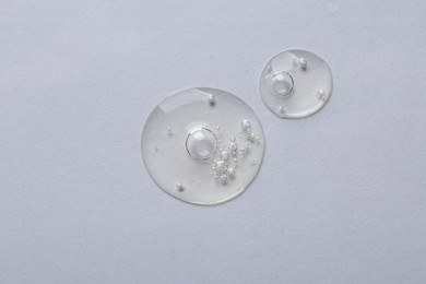 Drops of cosmetic serum on white background, top view