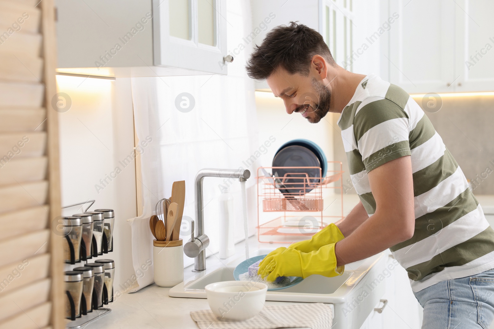 Photo of Man washing plate above sink in kitchen