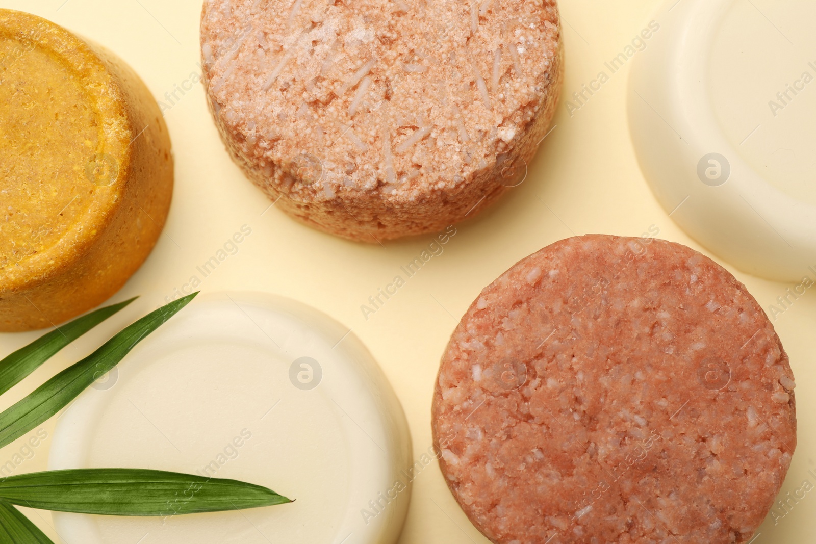 Photo of Flat lay composition of solid shampoo bars and leaf on beige background. Hair care