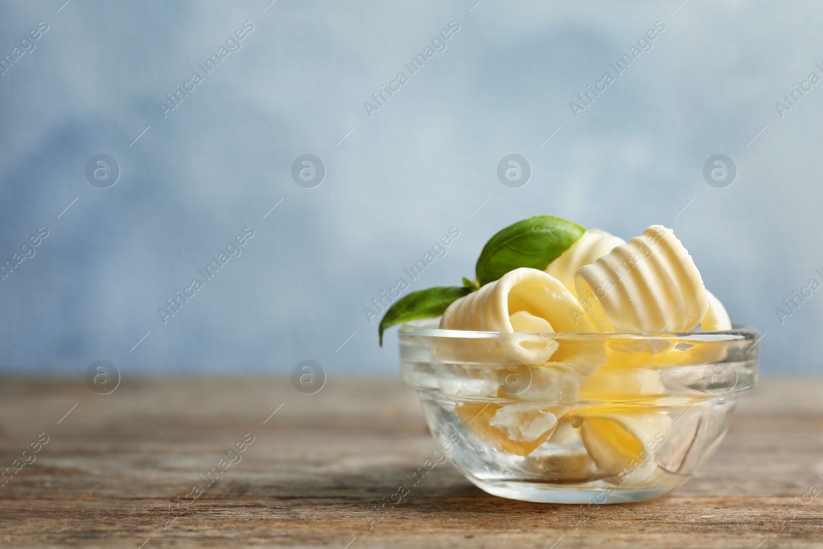 Photo of Bowl with tasty butter curls on table