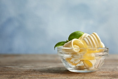 Photo of Bowl with tasty butter curls on table