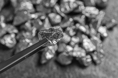 Photo of Tweezers with silver nugget on blurred background, closeup. Space for text