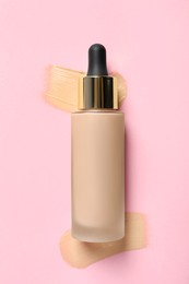 Photo of Liquid foundation and swatches on pink background, top view