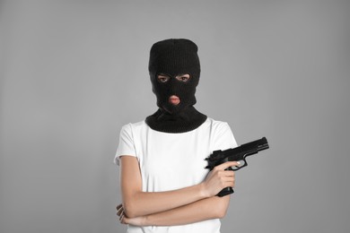 Photo of Woman wearing knitted balaclava with gun on grey background