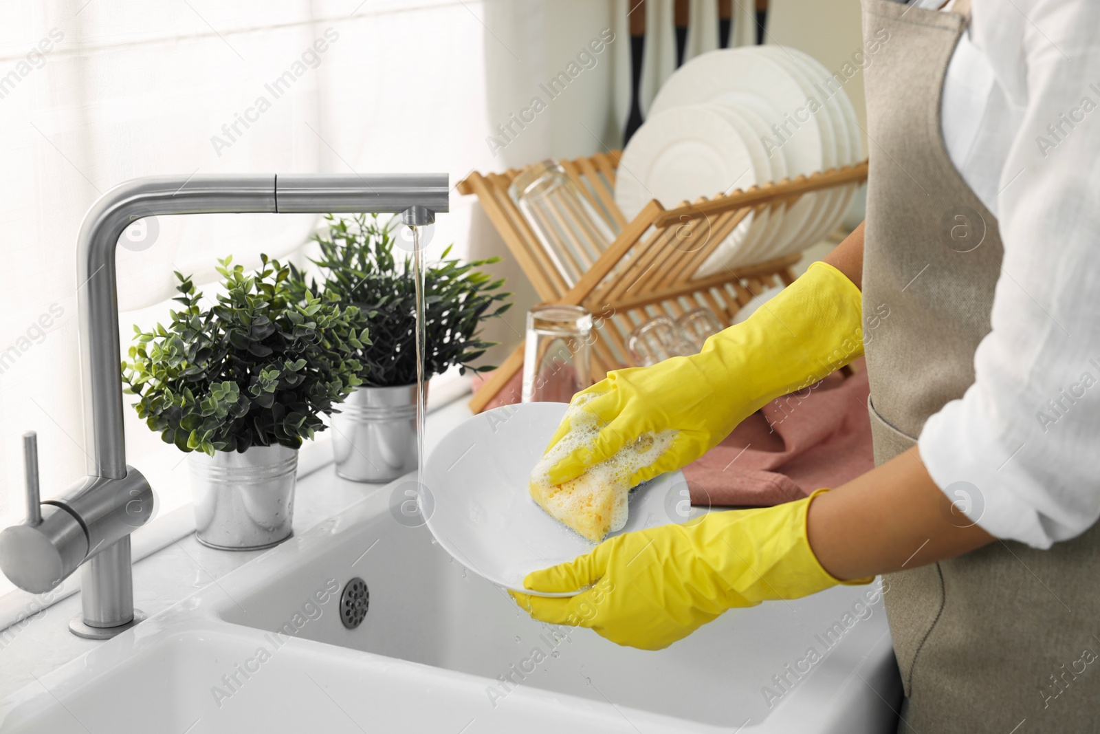 Photo of Woman washing bowl at sink in kitchen, closeup