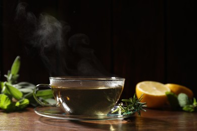 Cup of aromatic herbal tea and rosemary on wooden table