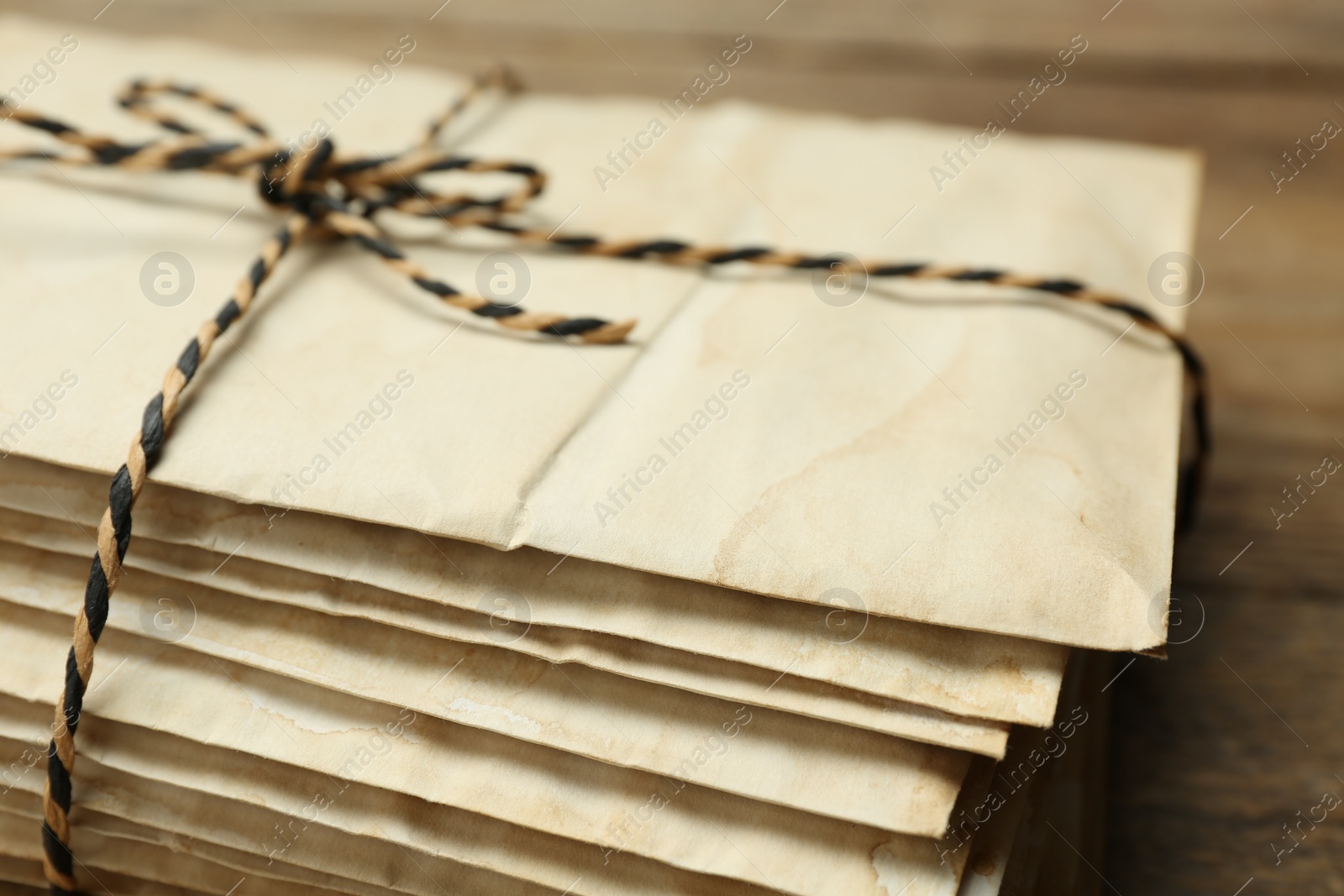 Photo of Stack of old letters tied with string on wooden table, closeup