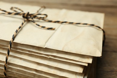 Stack of old letters tied with string on wooden table, closeup
