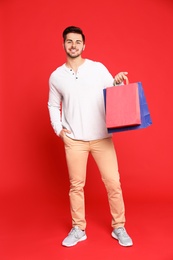 Photo of Full length portrait of young man with paper bags on red background