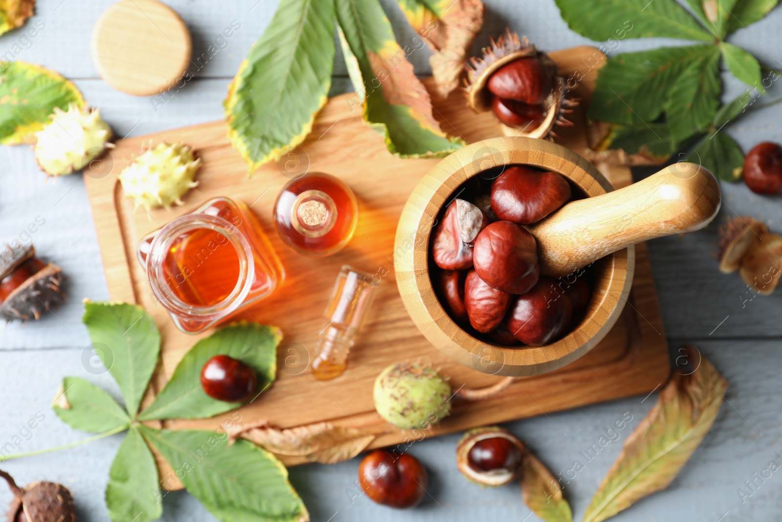 Photo of Flat lay composition with fresh horse chestnuts and extract on wooden table