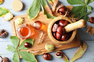 Photo of Flat lay composition with fresh horse chestnuts and extract on wooden table