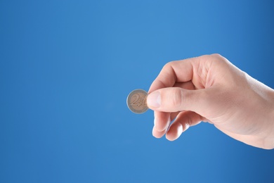 Photo of Man holding coin in hand on color background, closeup. Space for text