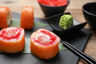 Photo of Delicious sushi rolls with tobiko on wooden table, closeup