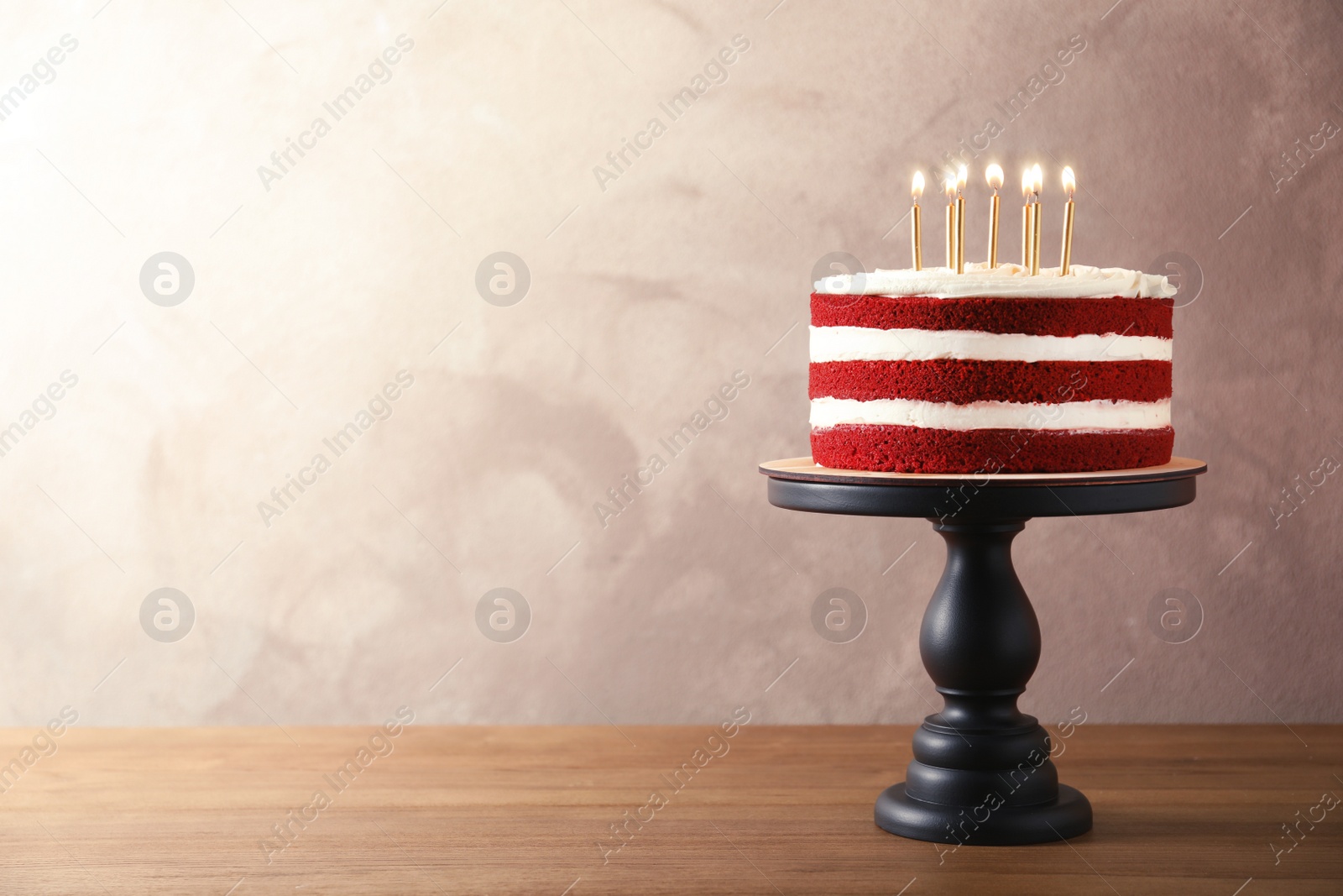 Photo of Delicious homemade red velvet cake with candles on table against color background. Space for text