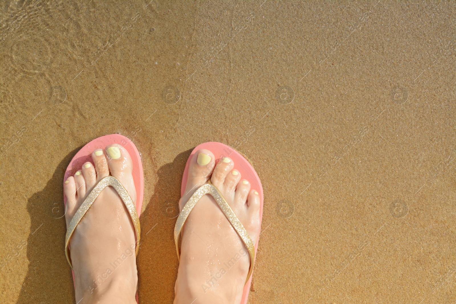 Photo of Woman wearing stylish flip flops on sandy beach, top view. Space for text