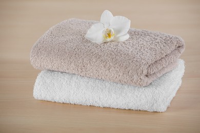 Soft folded towels with orchid flower on wooden table