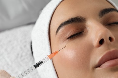 Photo of Young woman getting facial injection in clinic, closeup. Cosmetic surgery