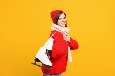 Photo of Happy woman with ice skates on yellow background