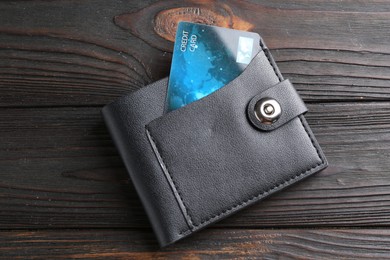 Credit card in leather wallet on wooden table, top view