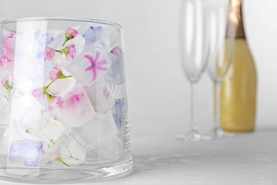 Glass vase with floral ice cubes on table. Space for text