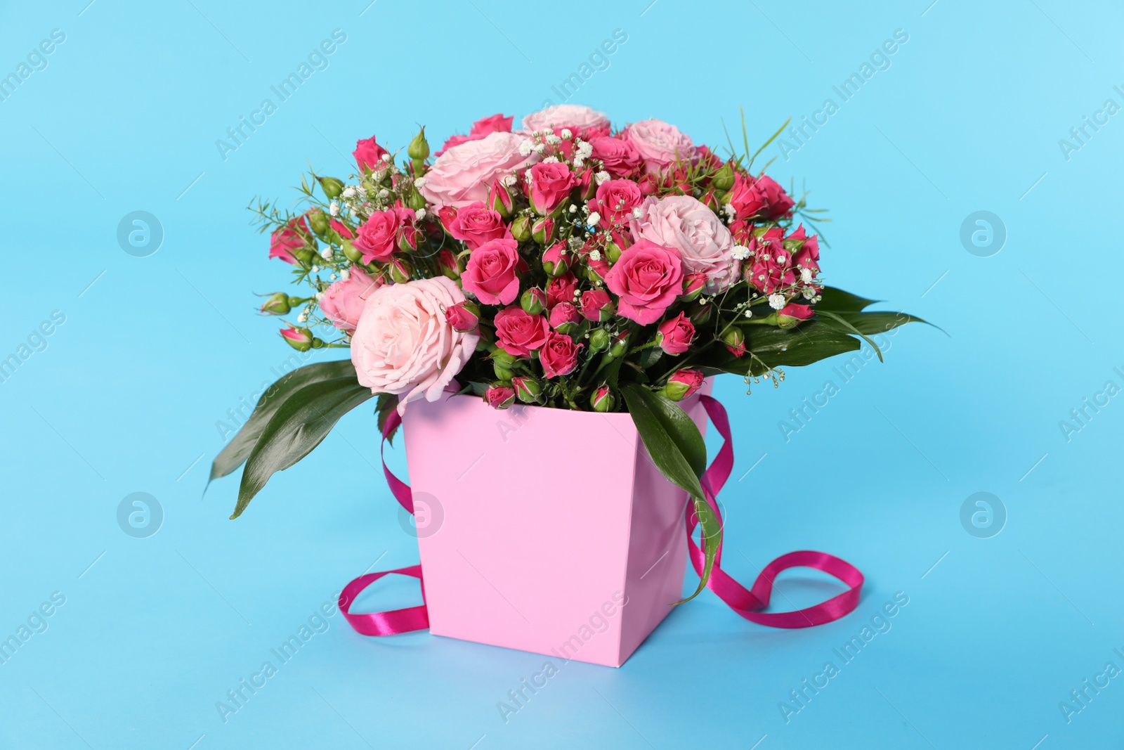 Photo of Beautiful bouquet of flowers in paper gift box on color background