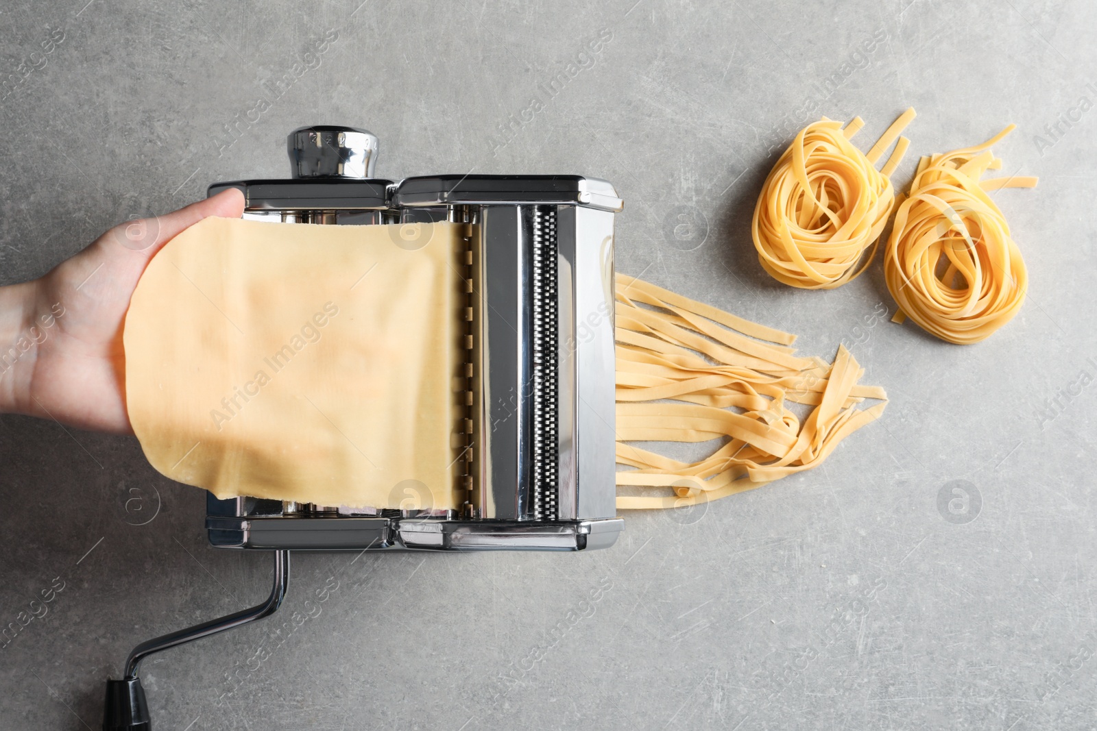 Photo of Young man preparing noodles on pasta maker at table, top view