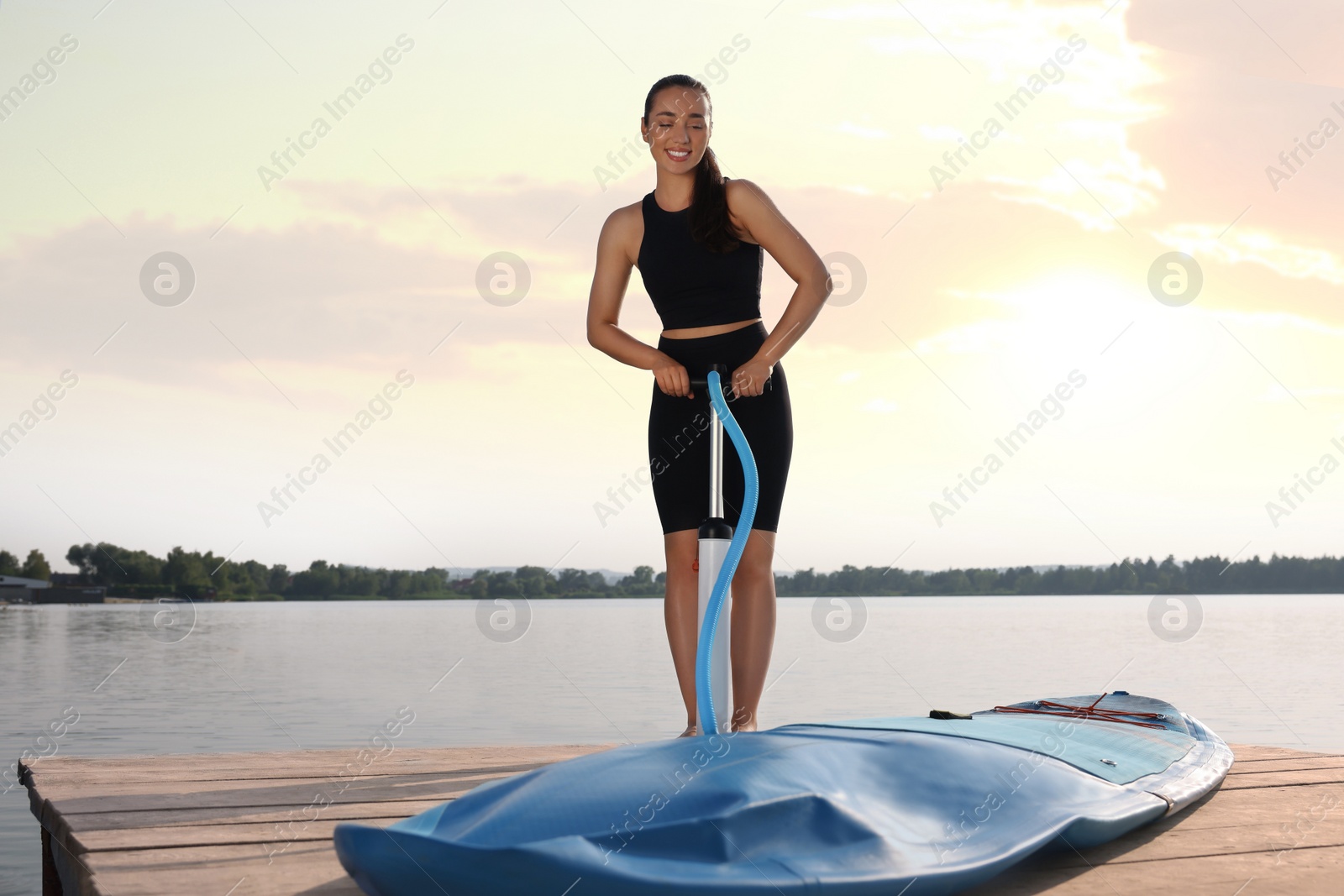 Photo of Woman pumping up SUP board on pier