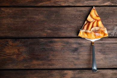 Slice of delicious fresh peach pie on wooden table, top view. Space for text