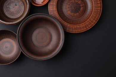Bowls and plates on black background, flat lay. Space for text