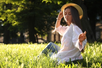 Photo of Young woman in straw hat sitting outdoors on sunny day, space for text
