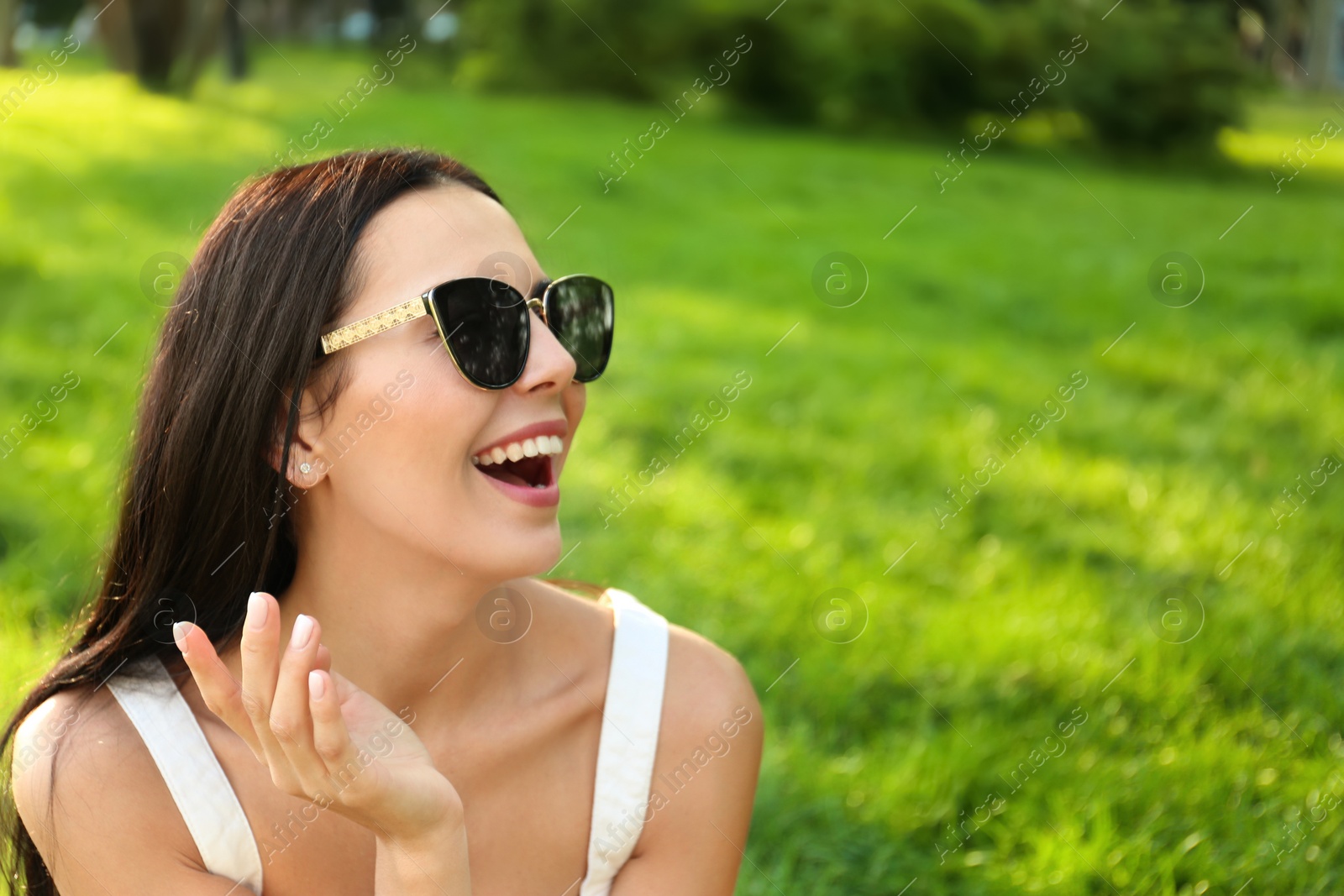 Photo of Beautiful young woman wearing stylish sunglasses in park. Space for text