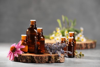 Bottles with essential oils and flowers on light table. Space for text