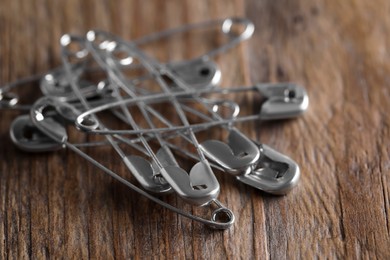 Photo of Pile of safety pins on wooden table, closeup