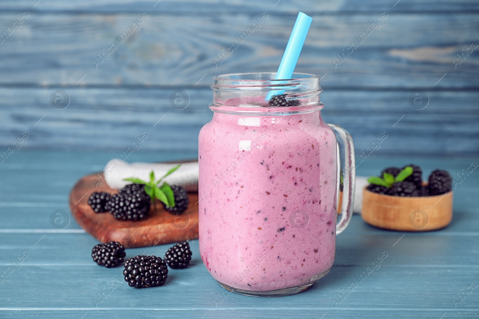 Photo of Delicious blackberry smoothie in mason jar on blue wooden table
