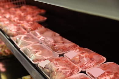 Photo of Shelf with packed chicken meat in supermarket