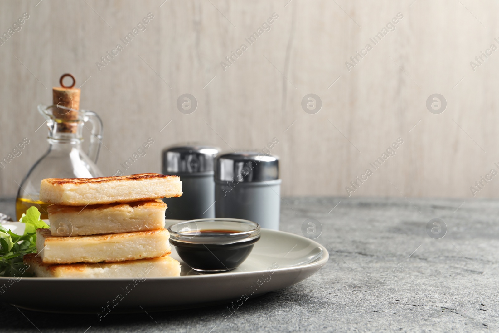 Photo of Delicious turnip cake with arugula served on grey table. Space for text