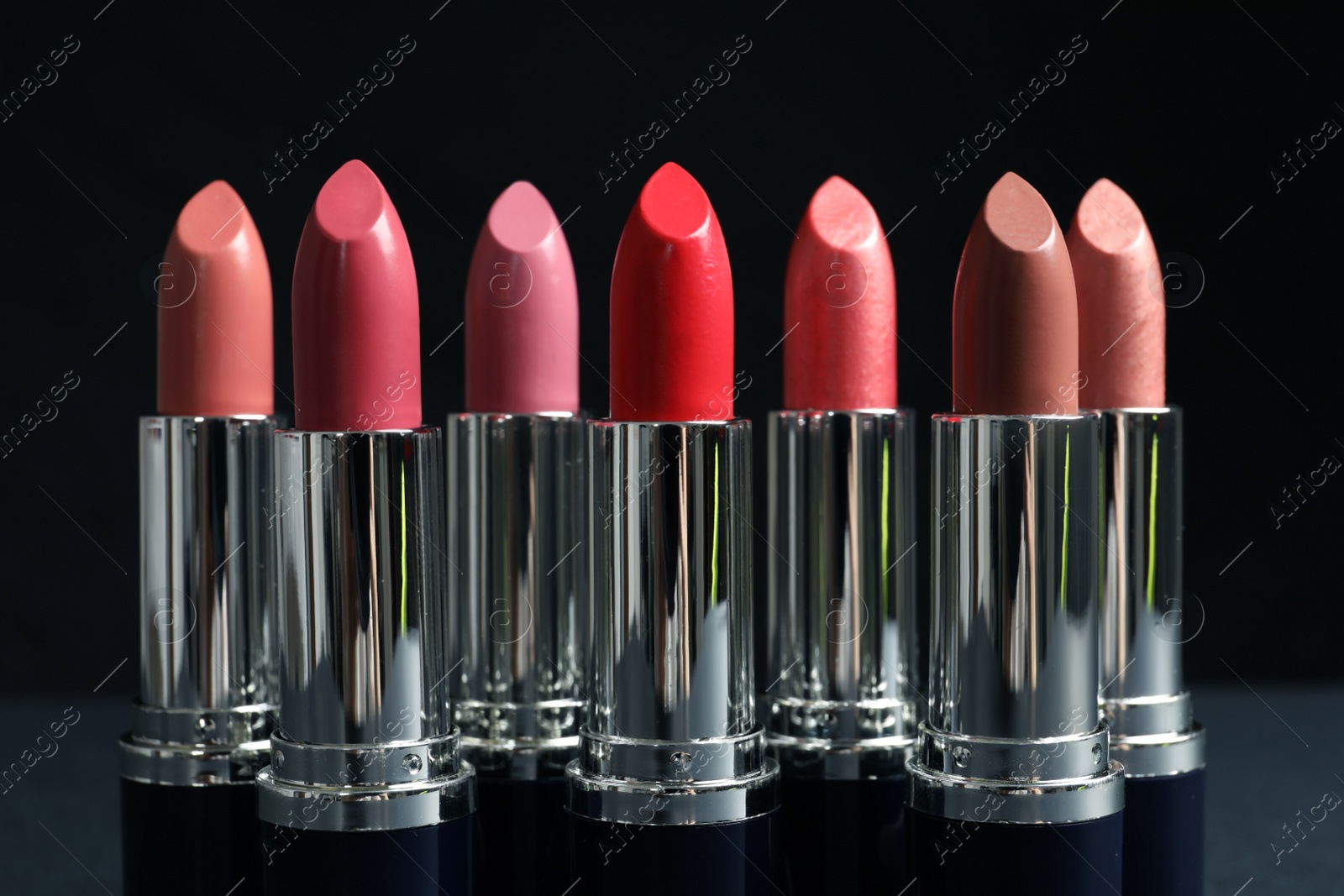 Photo of Different lipsticks on table against dark background