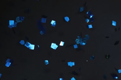 Photo of Shiny blue confetti falling down on black background