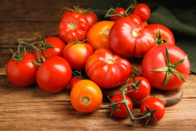 Many different ripe tomatoes on wooden table