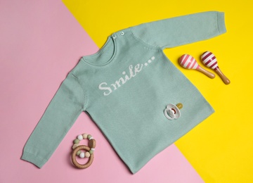 Flat lay composition with sweater and children's toys on color background