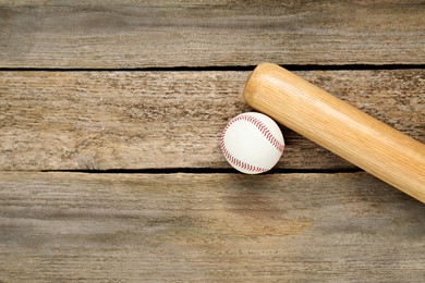 Photo of Baseball bat and ball on wooden table, top view with space for text. Sports equipment