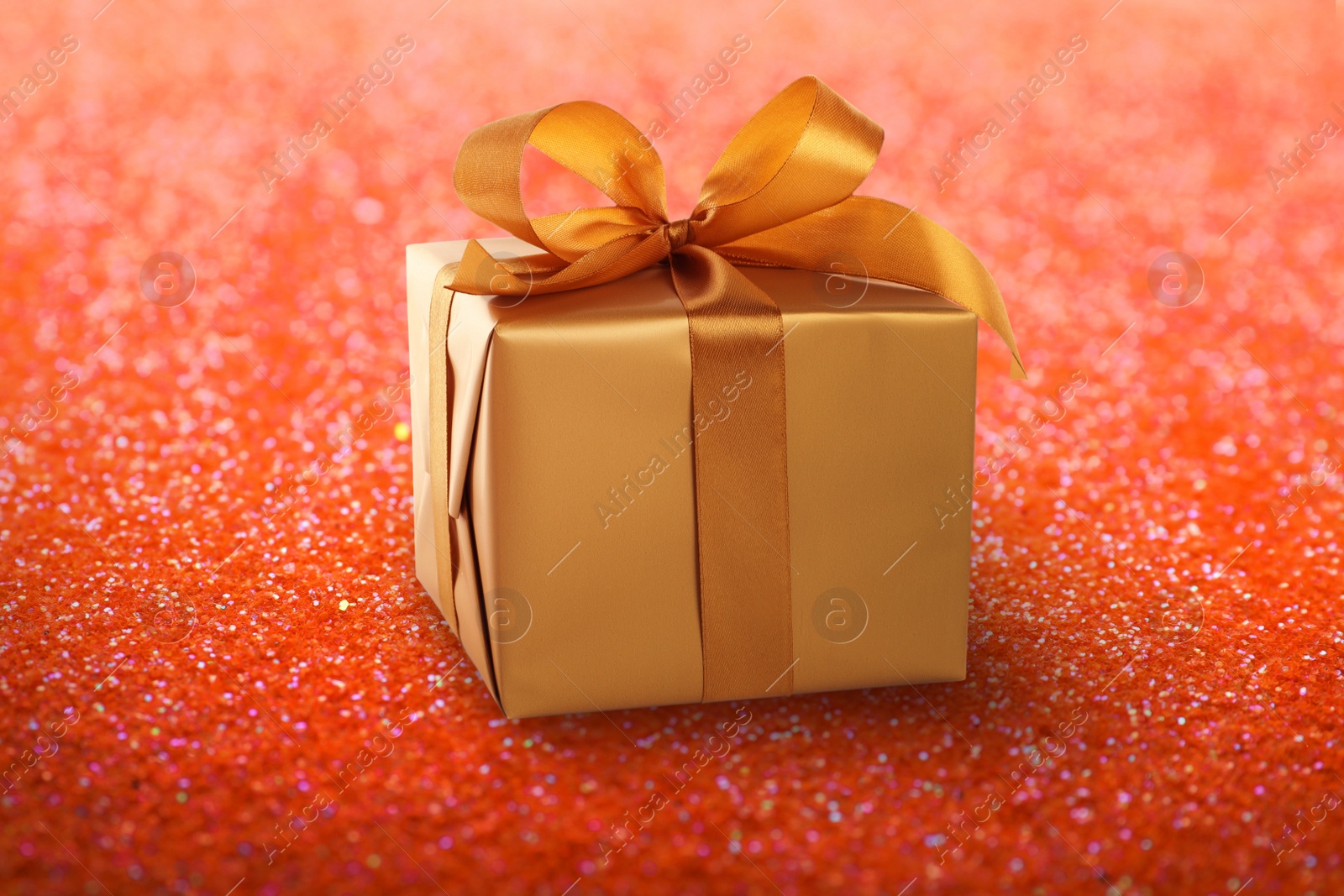 Image of Beautiful gift box on shiny red glitters. Bokeh effect 