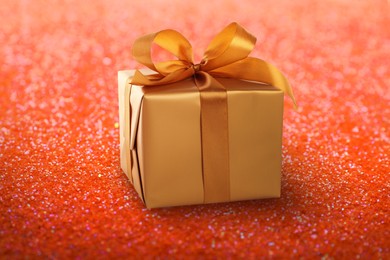 Beautiful gift box on shiny red glitters. Bokeh effect 