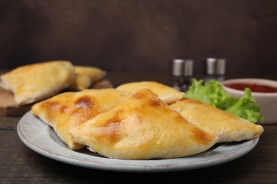 Photo of Delicious samosas and lettuce on wooden table