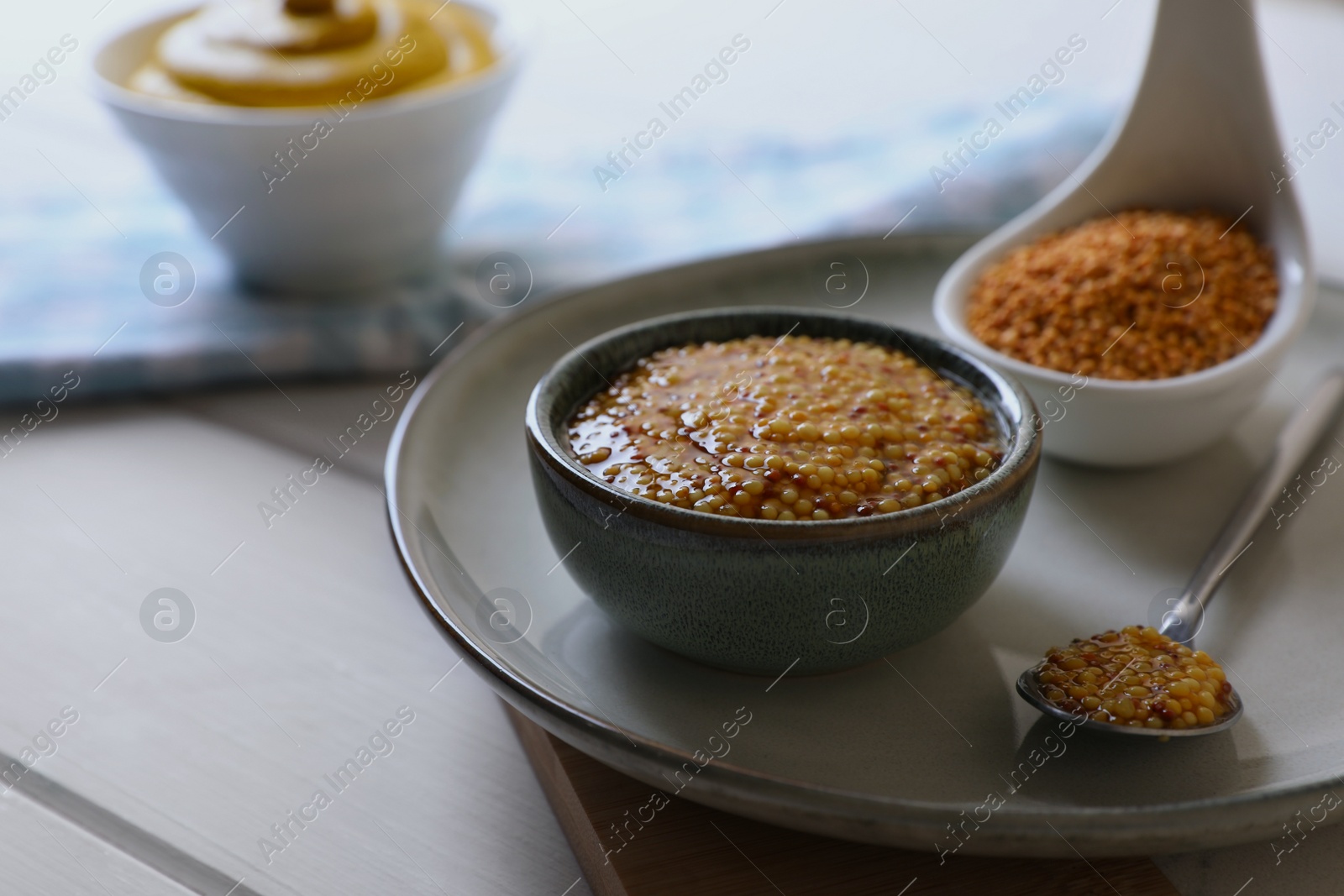 Photo of Bowl and spoon of whole grain mustard on wooden table. Space for text