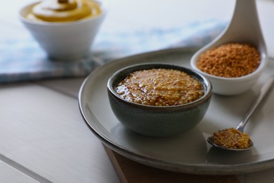 Bowl and spoon of whole grain mustard on wooden table. Space for text